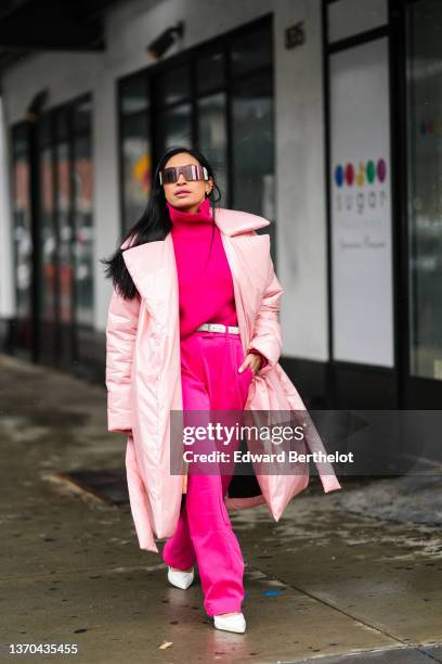 Miki Cheung wears black futurist sunglasses, a neon pink turtleneck pullover, a white leather belt from Saint Laurent Paris, matching neon pink large...