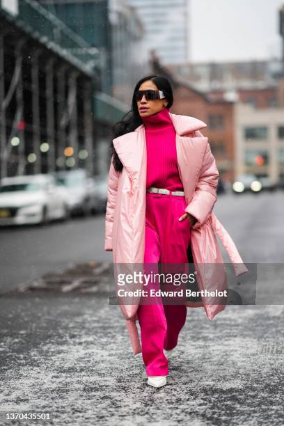Miki Cheung wears black futurist sunglasses, a neon pink turtleneck pullover, a white leather belt from Saint Laurent Paris, matching neon pink large...