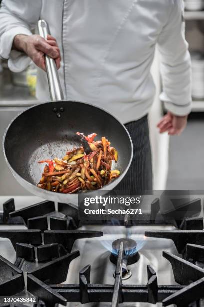 chef prepares a meal in a kitchen - wok stockfoto's en -beelden