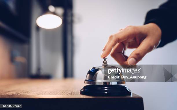 close up of someone hand trying to call hotel reception by ringing front desk bell. - värdshus bildbanksfoton och bilder