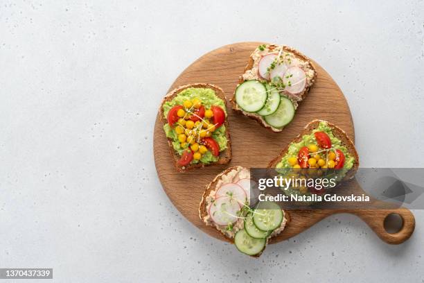 four grain bread slices with cream cheese and avocado spread. vegetables, chickpea and micro-green - grillad sandwich bildbanksfoton och bilder