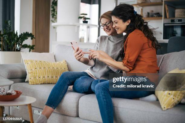 happy mother and daughter using smartphone together - mother media call stock pictures, royalty-free photos & images