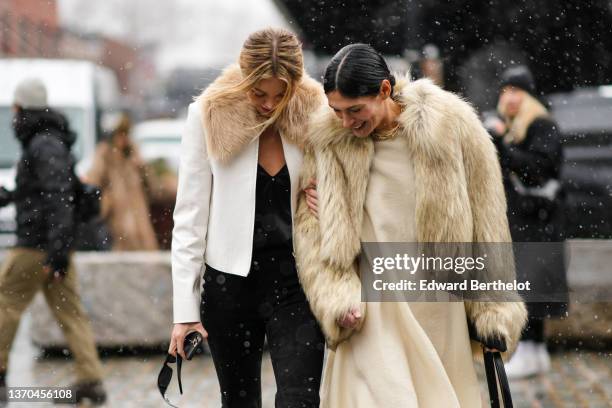 Guest wears a black V-neck satin t-shirt, a white leather with brown fur collar jacket, black denim jeans pants, black sunglasses, Athena Calderone...