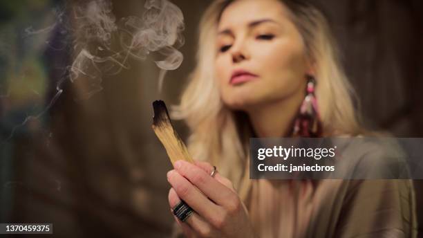 meditative space in desert tent. serene woman smudging with palo santo and inhaling the smoke - smudging ceremony stock pictures, royalty-free photos & images