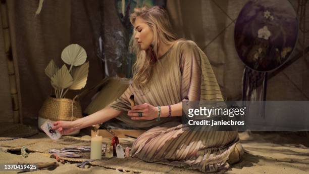 meditative space in desert tent. serene woman smudging with palo santo and using divination cards - smudging ceremony stock pictures, royalty-free photos & images