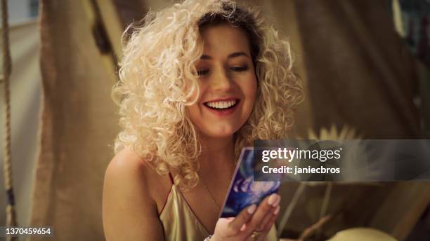 meditative space in desert tent. woman during soul journey with divination cards. holding card and smiling - tarot lady stock pictures, royalty-free photos & images
