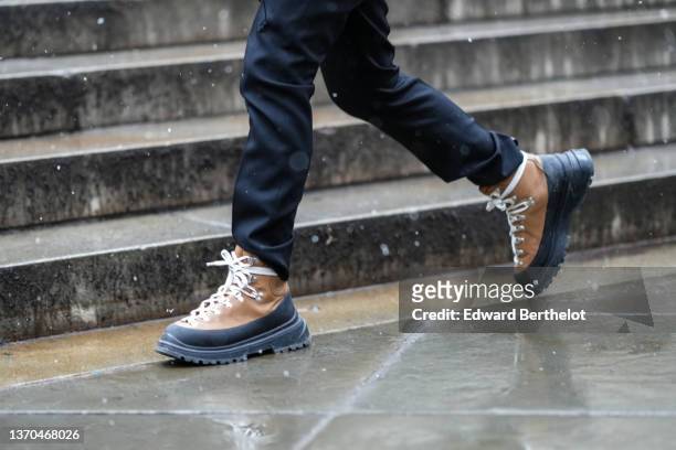 Guest wears black pants, brown suede and black soles laces ankle boots, outside Ulla Johnson, during New York Fashion Week, on February 13, 2022 in...