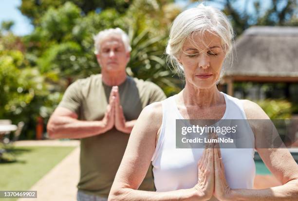 shot of a mature couple meditating together outdoors - training grounds stockfoto's en -beelden