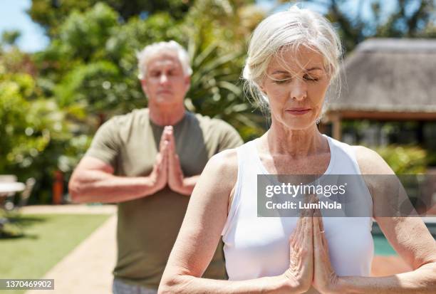 shot of a mature couple meditating together outdoors - couple doing yoga stock pictures, royalty-free photos & images