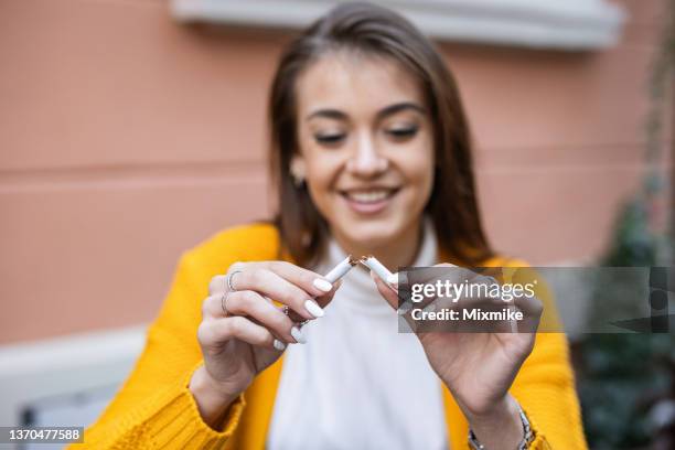 woman in yellow cardigan quit smoking - broken cigarette stock pictures, royalty-free photos & images