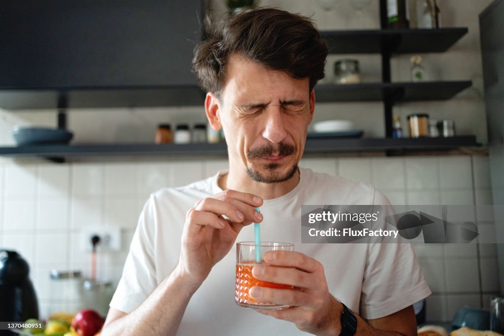 Man making the face after he tasted the juice