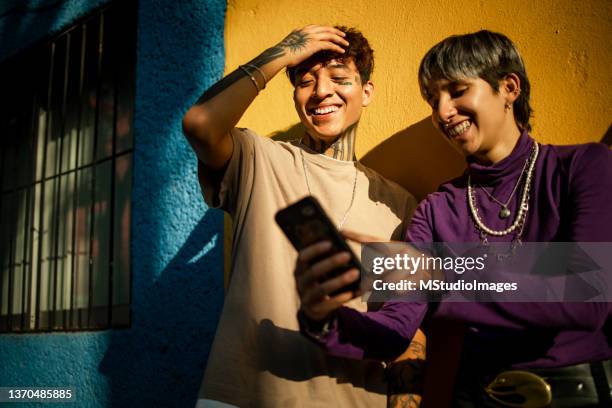 dos amigos observando a teléfono móvil - purple mexican fotografías e imágenes de stock