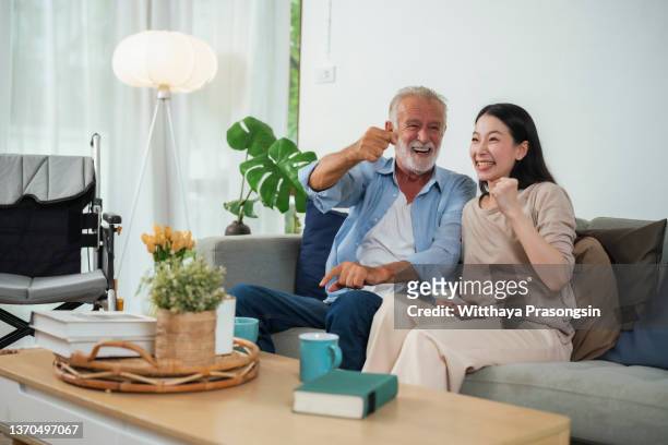 father and daughter watching tv laughing happily at home - guardians of heritage screening by german tv channel history stockfoto's en -beelden