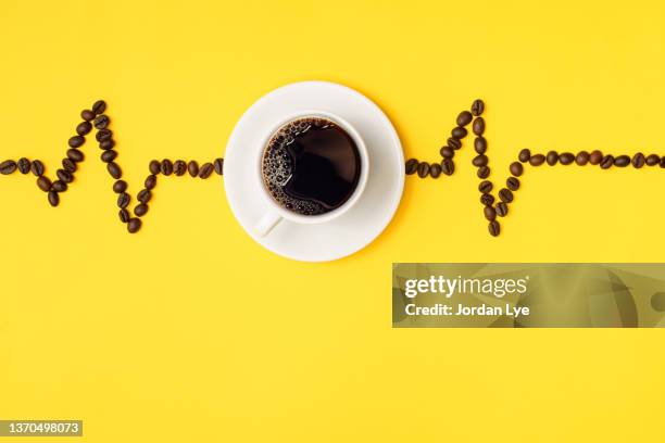 cup of coffee with a conceptual pulse trace with coffee bean - koffeinmolekül stock-fotos und bilder