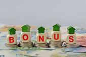 Wooden house and blocks with the word Bonus on coins and banknotes - Concept of home renovation bonus