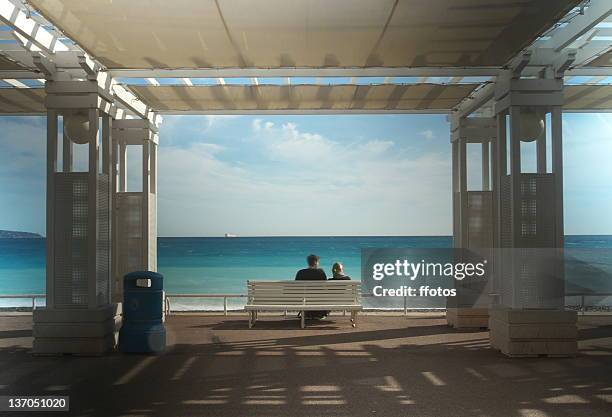 couple sitting on bench - nice promenade des anglais photos et images de collection