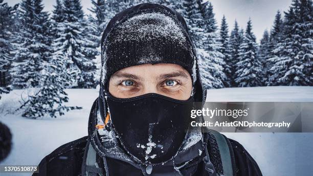 male snowboarder covered in snow smiling in winter. - bivakmuts stockfoto's en -beelden