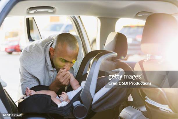 after putting baby in safety seat, father kisses her hand - guy in car seat stockfoto's en -beelden
