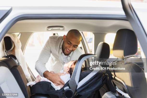 father smiles while putting baby in safety seat - guy in car seat stockfoto's en -beelden