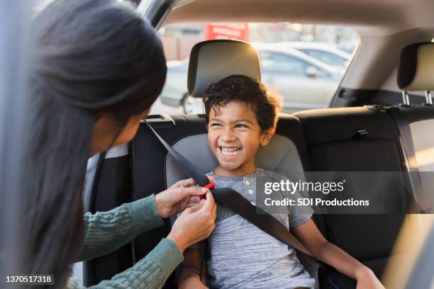 unrecognizable mother adjusts seat belt for young son - kid car safety stock pictures, royalty-free photos & images