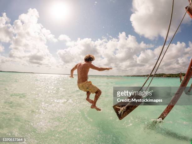 junger mann springt an einem sonnigen tag von einer schaukel in einer wunderschönen lagune - yucatan stock-fotos und bilder