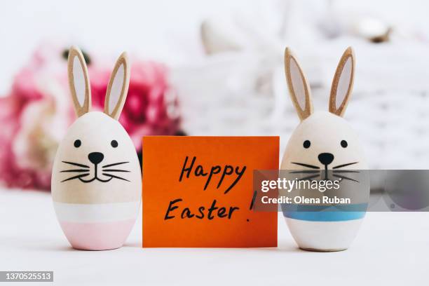 happy easter! label and bunnies against roses and basket. - easter eggs basket stock-fotos und bilder