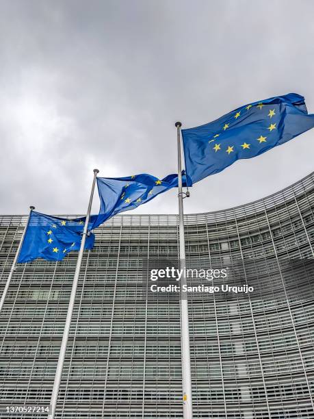 european union flags waiving at berlaymont building of the european commission - legislation stock-fotos und bilder
