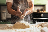 Chef's hands spraying flour over the dough