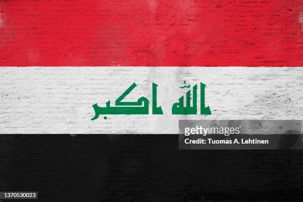 full frame photo of a weathered flag of iraq painted on a plastered brick wall. - iraq flag stock pictures, royalty-free photos & images