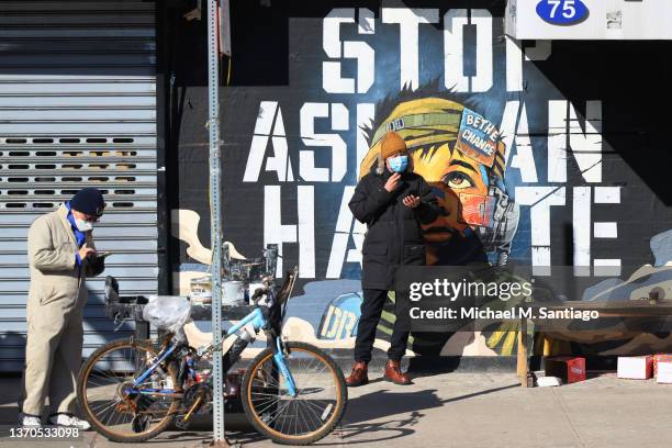 People stand in front of a "Stop Asian Hate" mural as people gather for a rally protesting violence against Asian-Americans at Sara D. Roosevelt Park...