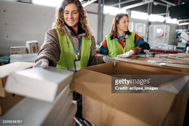 women working in distribution warehouse - geblokt pak stockfoto's en -beelden