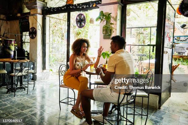 wide shot of smiling couple in discussion while sharing drinks in cafe - mexican beer stock-fotos und bilder