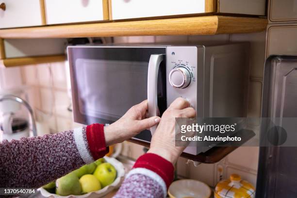 old woman closing the microwave in her kitchen - old person kitchen food ストックフォトと画像