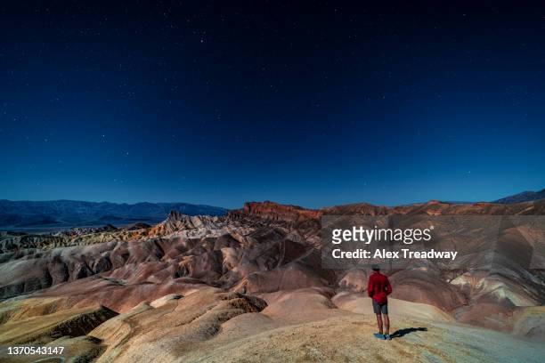 a man looks out at surreal and dramatic landscape at night in death valley - zabriskie point stock pictures, royalty-free photos & images