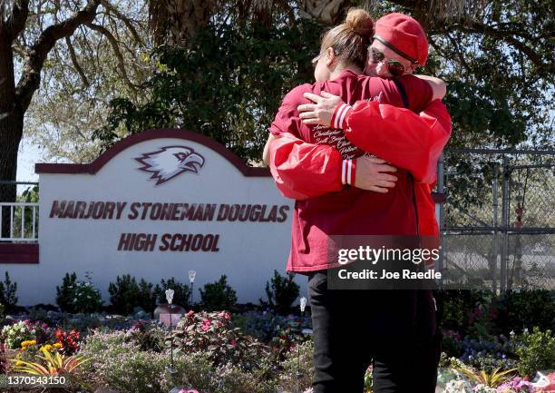 Iris Diaz hugs Mark Muniz from the Guardian Angels as she visits a memorial in front of Marjory Stoneman Douglas High School to honor those killed...