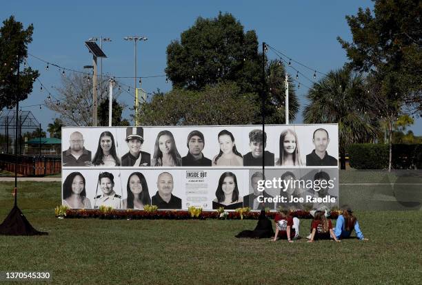 People sit in front of a photo display of the 17 people killed at Marjory Stoneman Douglas High School during a mass shooting on February 14, 2022 in...