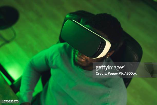 black man sitting vr game neon lights - portrait shot - lunettes de pilote de course photos et images de collection