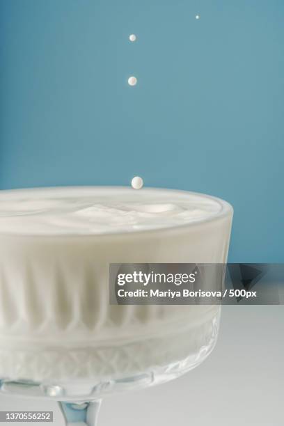 milk pours into a beautiful crystal glass on a blue background and - hemp milk stock pictures, royalty-free photos & images