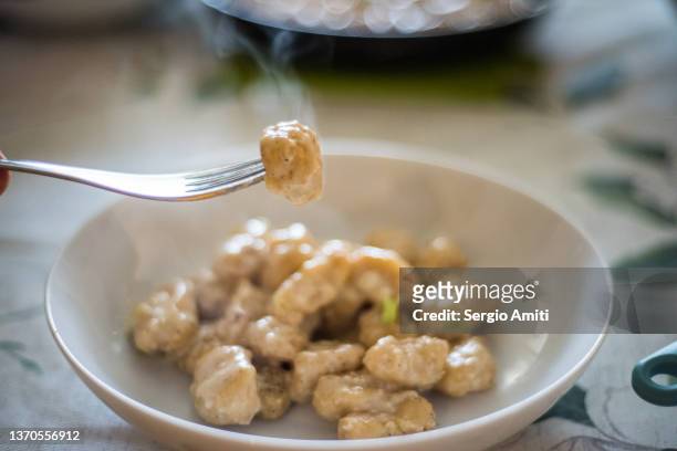 fork holding a gnocchi quattro formaggi with chives - gorgonzola stock pictures, royalty-free photos & images