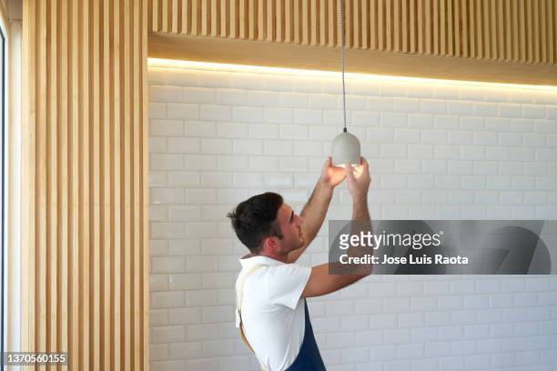 working on electricity. man changing lights. - led lampe photos et images de collection