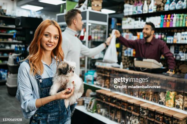 happy couple with their puppies buying toys and dog food in pet shop. - small pets stock pictures, royalty-free photos & images