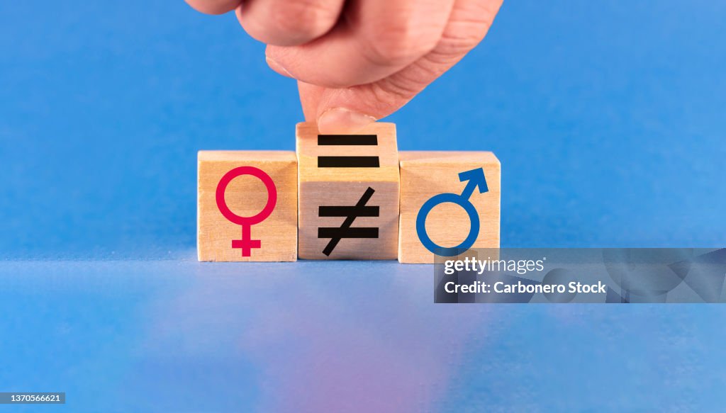 Concept of gender equality. A hand changes an unequal sign to an equal sign between male and female symbols.