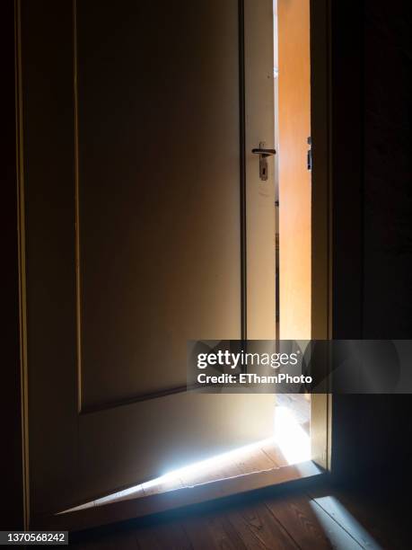 bright sunlight coming through crack of ajar door to dark attic - light coming through doors stock-fotos und bilder