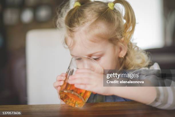 baby girl blonde in home interior , drinking apple juice - apple juice stock pictures, royalty-free photos & images