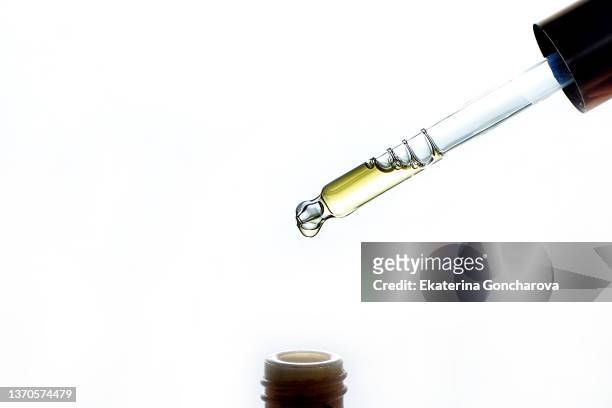 close-up of a drop of yellow oil in a glass pipette on a white background. - 血清樣本 個照片及圖片檔