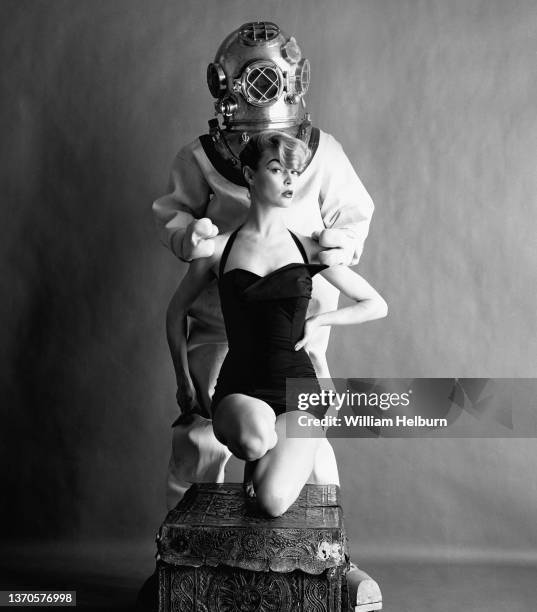 American model Jean Patchett , in a maillot swimsuit, poses in front of an unidentified male model, who stands behind her, in standard diving dress,...