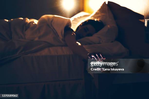 morning shot of a person lying in bed tapping phone, turning off the alarm - morning foto e immagini stock