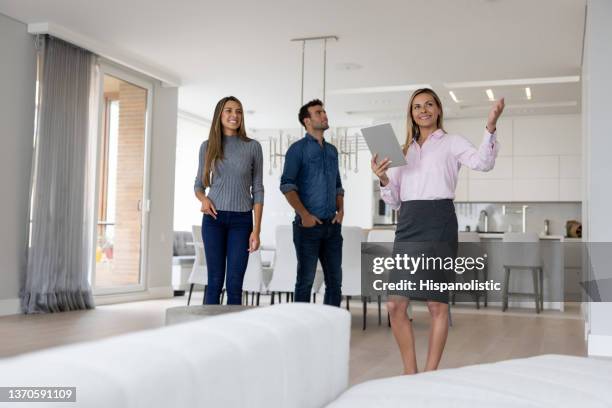 real estate agent showing a property to a couple buying a house - real estate agent imagens e fotografias de stock