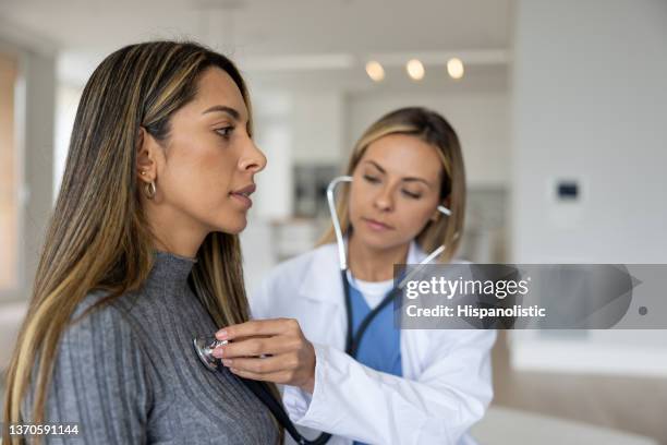 arzt bei einem hausbesuch, der eine ärztliche untersuchung durchführt - adult patient with doctor and stethoscope stock-fotos und bilder