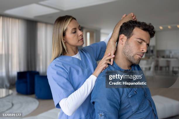 physical therapist helping of a patient with his stretching exercises at home - house call stockfoto's en -beelden